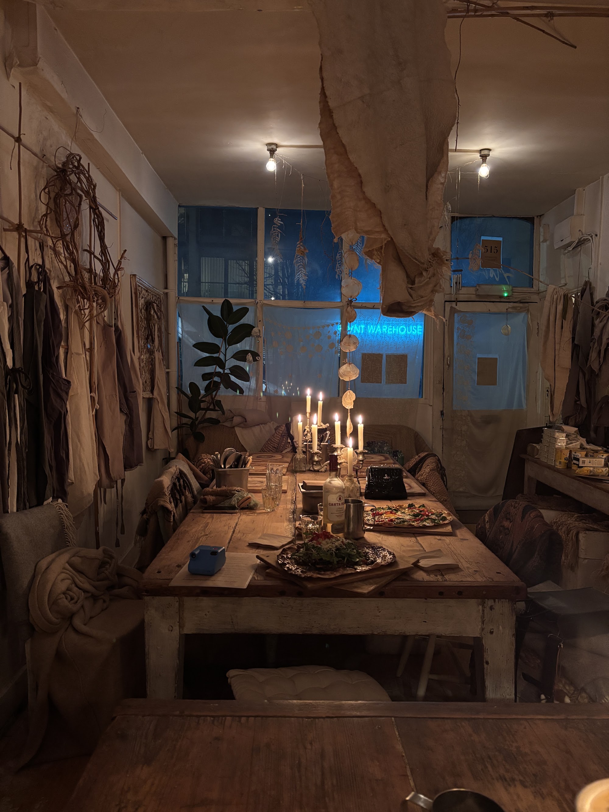 The candlelit interior of story deli's Cambridge Heath Road warehouse, with pizzas on a long wooden table