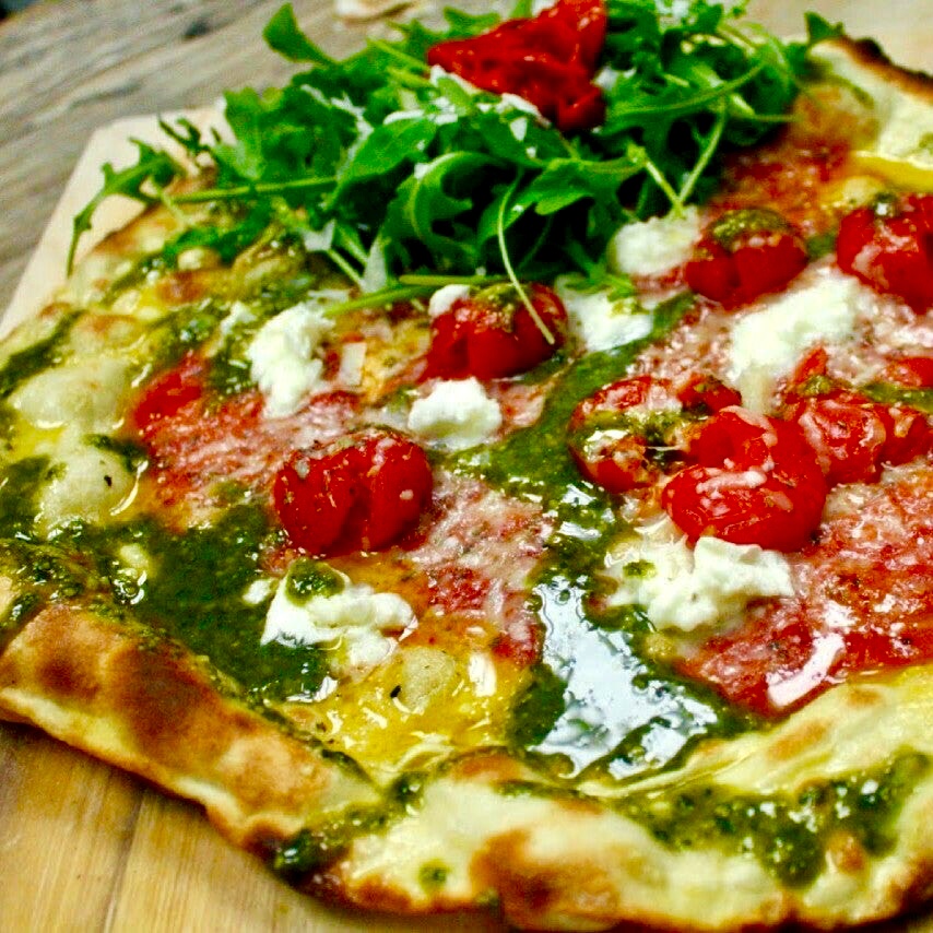 Close-up of a story deli pizza with rocket, roasted cherry tomatoes and torn mozzarella